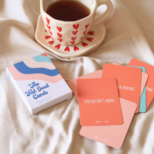 Set of cards with motivational messages next to a cup of tea on a light surface Feel good cards on bed with coffee cup