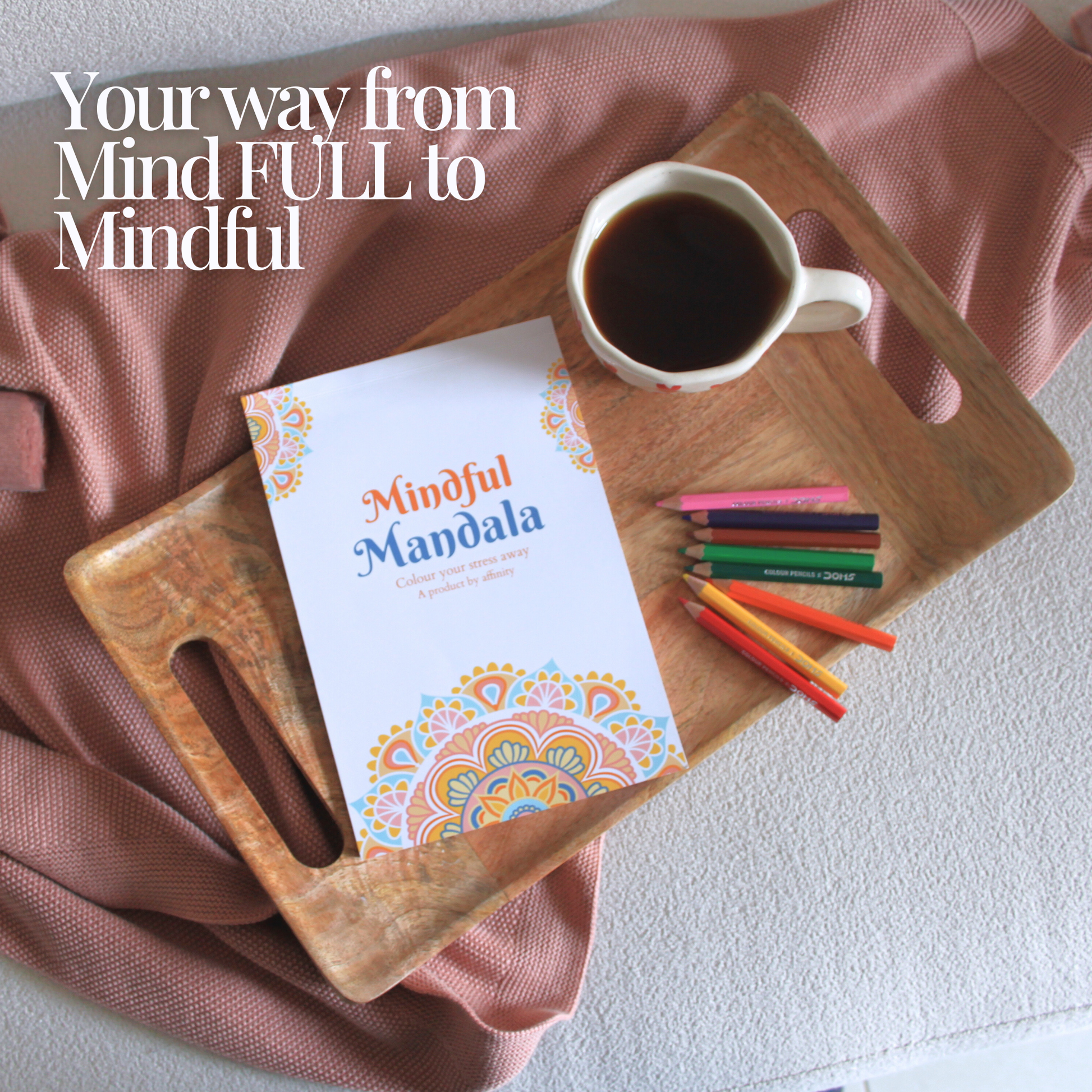 mindful mandala book with open pencil colors and a cup of black coffee on a wooden tray on a pink bedsheet. affinity mindful mandala in tray with coffee cup for stress relief