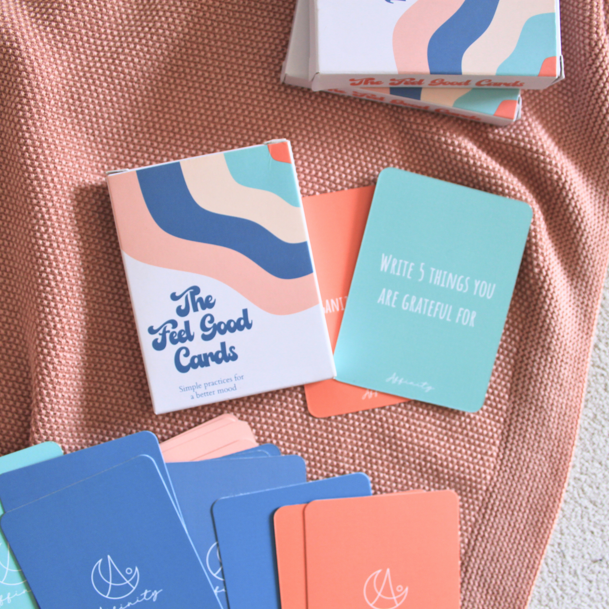 feel good cards box and feel good with fun science and psychology based activities spread on a pink throw to create an aesthetic image.